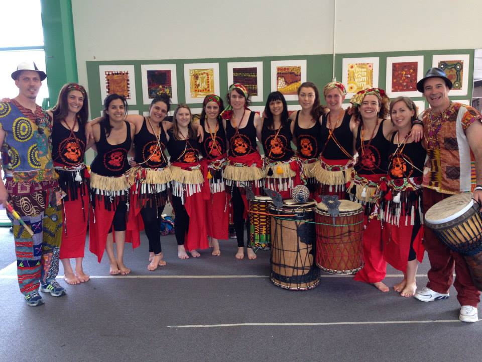 Group of dancers standing in a line with Melbourne Djembe singlets and raffia skirts