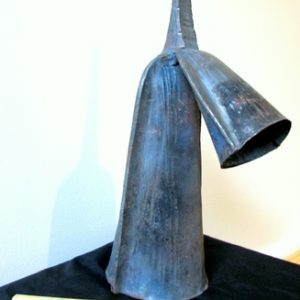 African double bell sitting on table with wooden stick next to it