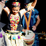 Dancer is costume playing dundun (African stick drum)