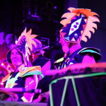 Two drummers in fluro African head pieces, playing African drums