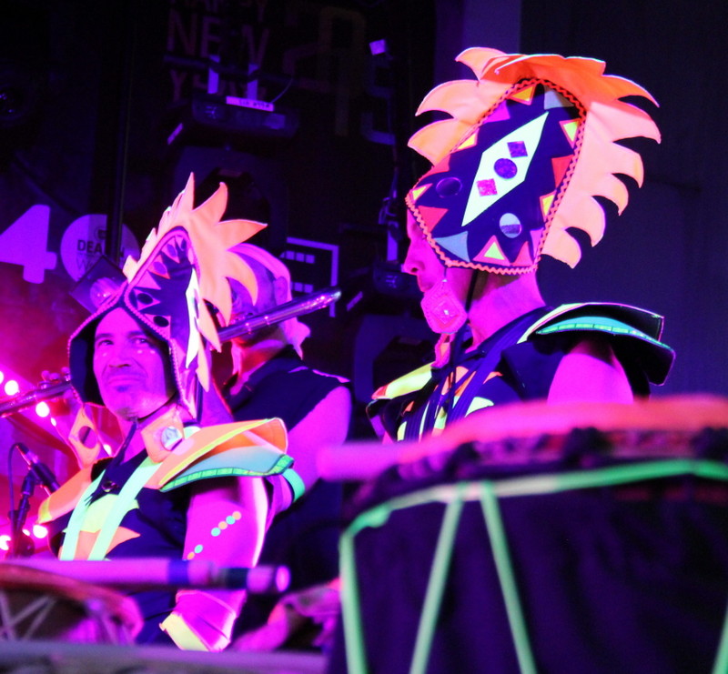 Two drummers in fluro African head pieces, playing African drums